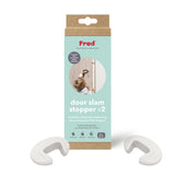 A package labeled Fred door slam stopper x2 with two white C-shaped door stoppers in front. The packaging shows a child reaching for a door, emphasizing finger protection and a child proof door solution. Suitable for ages 6 months and up.