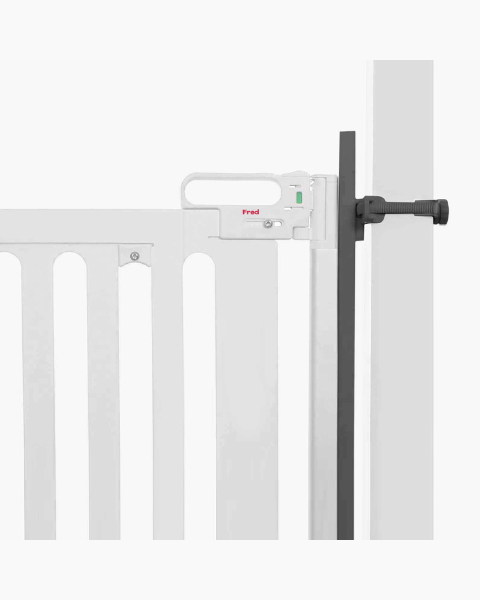 A white safety gate with a latch mechanism is attached to a doorway using a black adjustable pressure mount. The gate features vertical bars and is designed for child or pet safety.
